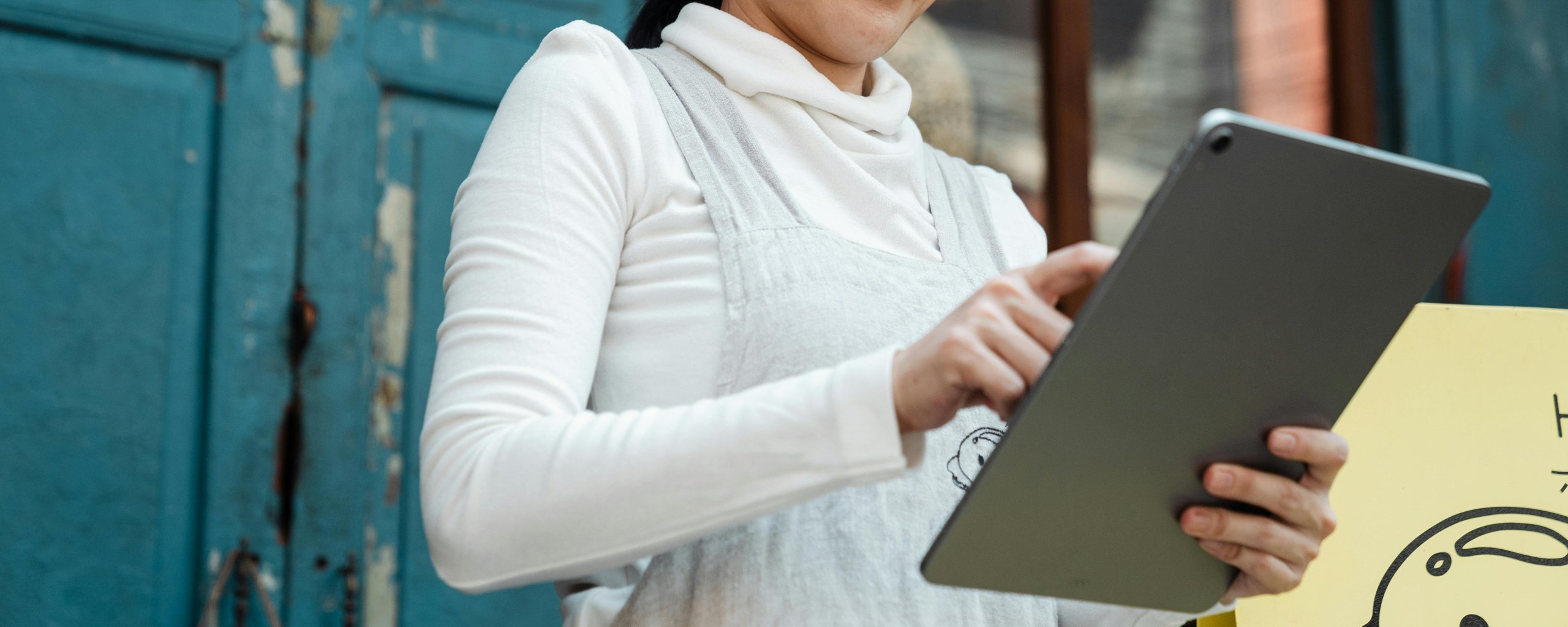 A woman stands holding a tablet computer